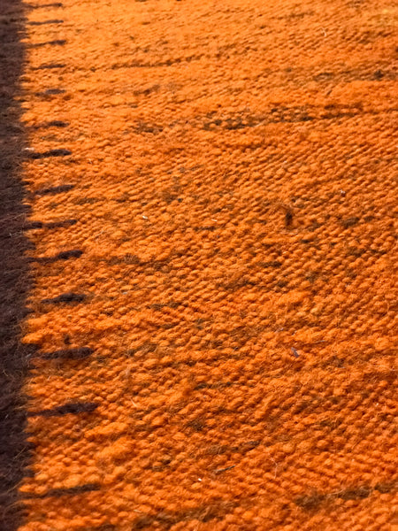 Orange wool rug with white fringe