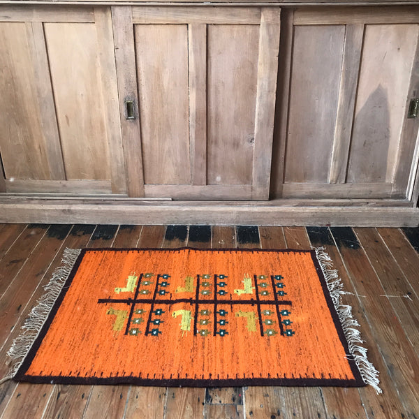 Orange wool rug with white fringe