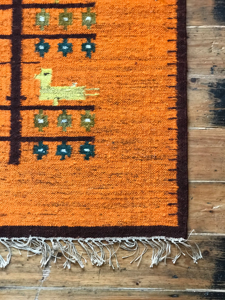 Orange wool rug with white fringe